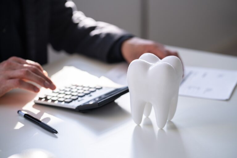 Tooth model in a desk with a view of someone using a calculator